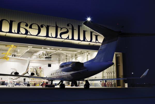 Exterior of Gulf Stream Service Center at night. Plane entering hangar.